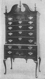 The general proportions, the broken pediment and torch or flame ornaments and drops, large brasses, and cabriole legs all show that this splendid example of a highboy belongs to the same time as the desk, about 1750.