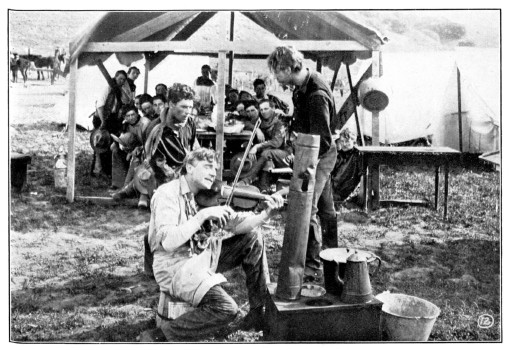 A man plays the violin at a campsite.