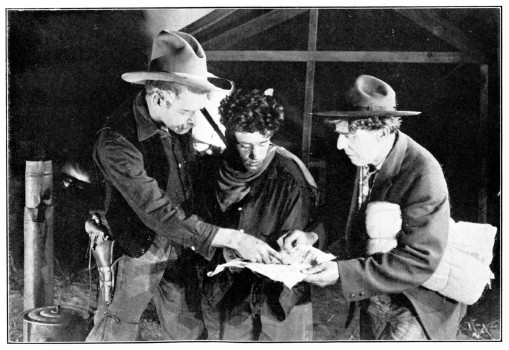 Three men look at a piece of paper.