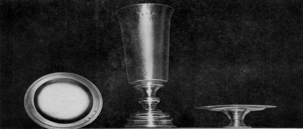 COMMUNION SERVICE IN USE AT SMITH'S HUNDRED, 1618.  This three piece communion service now at St. John's Church, Elizabeth City Parish, Hampton, Virginia, has the longest history of use in the United States of any church silver. The set, a gift to the church founded in 1618 at Smith's Hundred in Charles City County, was made possible by a legacy in the will (date 1617) of Mrs. Mary Robinson of London. Smith's Hundred renamed Southampton Hundred, 1620, was practically wiped out in the Indian Massacre of 1622. This communion set delivered in 1627 to the Court at Jamestown for safe keeping, supposedly, then was given to the second Elizabeth City Church built on Southampton (now Hampton) River. The inscription in one line on the base of the Chalice is: The Communion Cupp for Snt Marys Church in Smiths Hundred in Virginia. Hall marks on all three pieces bear London date-letters for 1618-19.  Courtesy Mrs. L. T. Jester and Mrs. P. W. Hiden