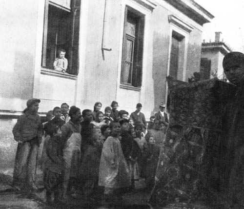 GREEK CHILDREN WERE GROUPED AROUND A PUNCH AND JUDY SHOW.