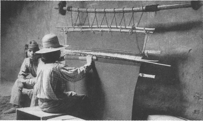 Copyright by H. S. Poley  A Hopi Indian weaving a rug on a hand loom in a deserted cave