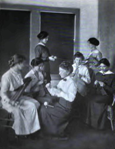 A Knitting Class at the Agricultural School. Note the splendid poise of the Country Girl in the background, how naturally and yet perfectly she is holding herself.