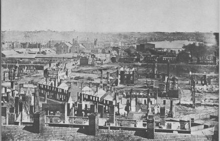 Richmond 1865—Gaunt remains cast their shadow over the former Confederate capital. The rampaging fire, started during the evacuation, leveled the waterfront and the business district.