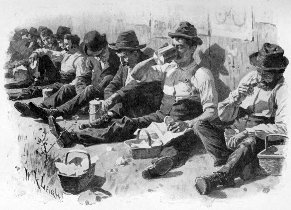 A long line of men sitting with their backs against a wall having lunch.