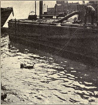 DIVER STANDING ON SUNKEN COAL BARGE.